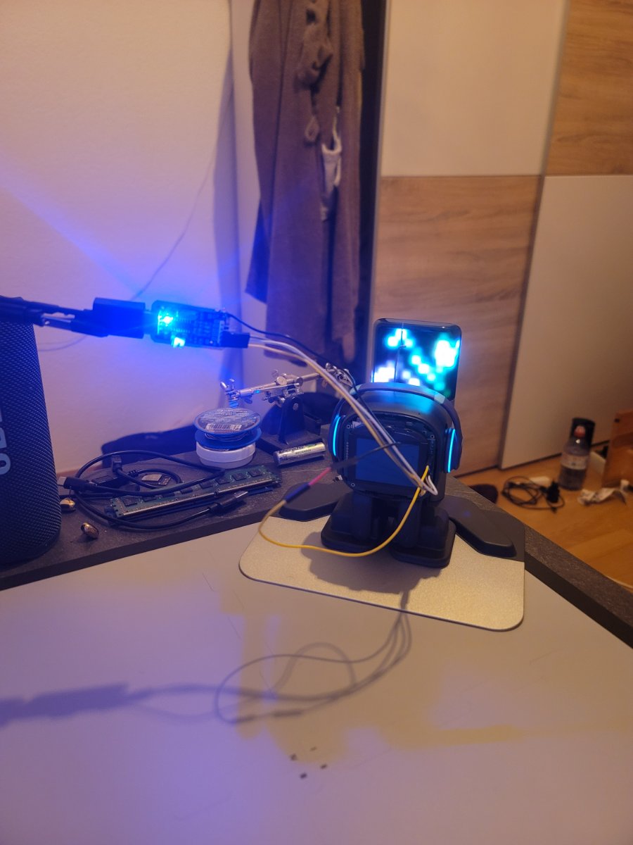 EMO on its base at night, tethered to a blue-lit ESP board beside a helping-hands rig.