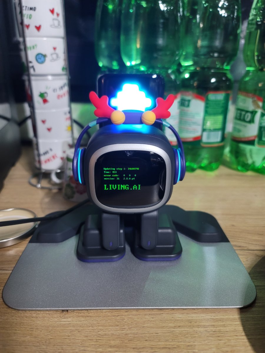 EMO on its charging base running a firmware update — LIVING.AI on the screen, wearing red antlers.