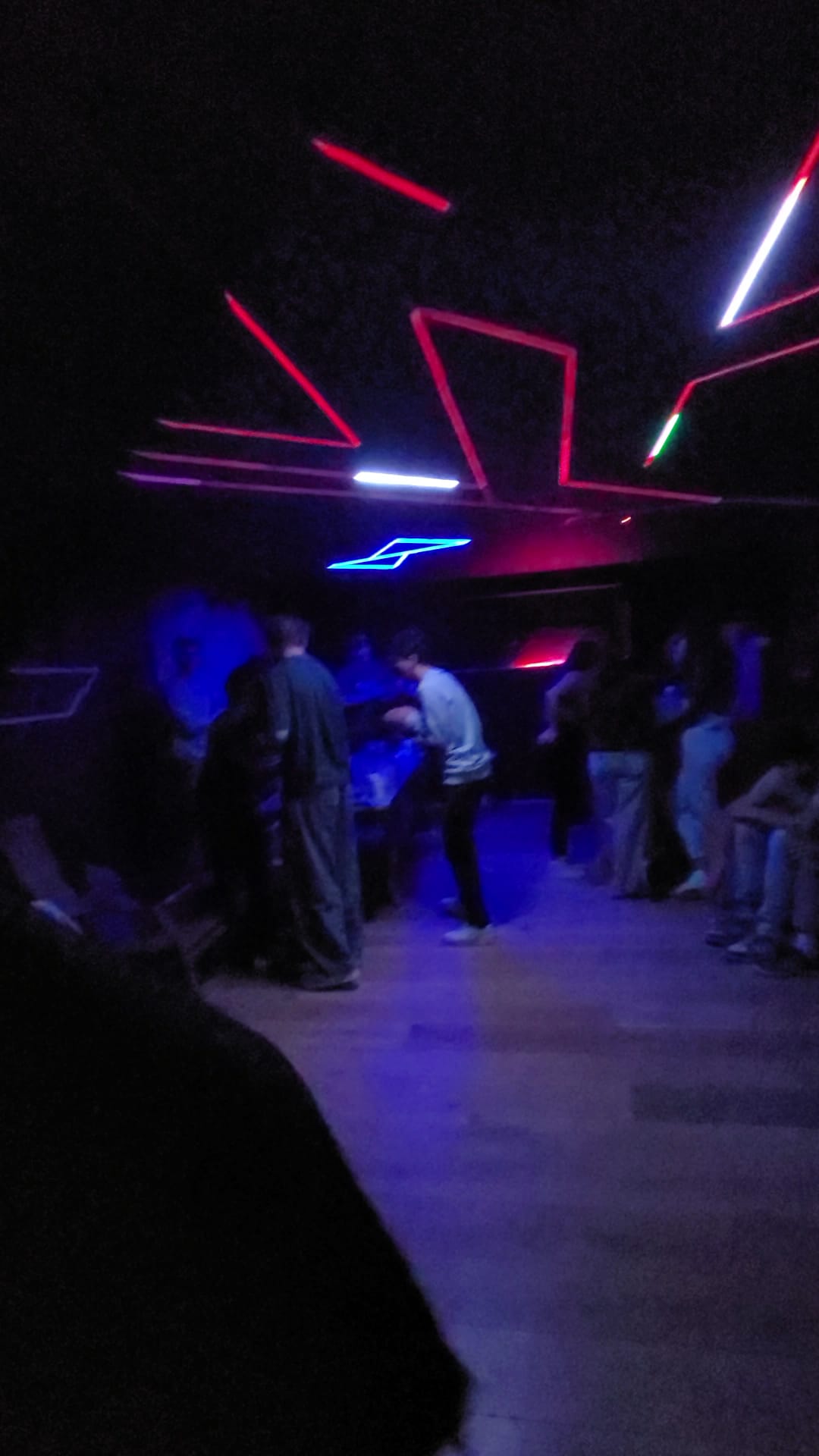 The finished room during a party, ceiling running red and blue over a full floor.